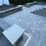 a stone patio with a bench and steps