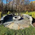 a circular fire pit surrounded by grass and trees