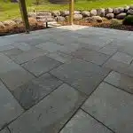 a stone patio with a tree in the background