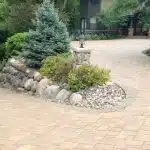 a stone driveway with trees and bushes