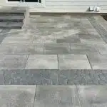 a grey stone patio with a white building