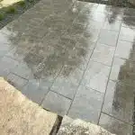 a wet stone patio with a few rocks